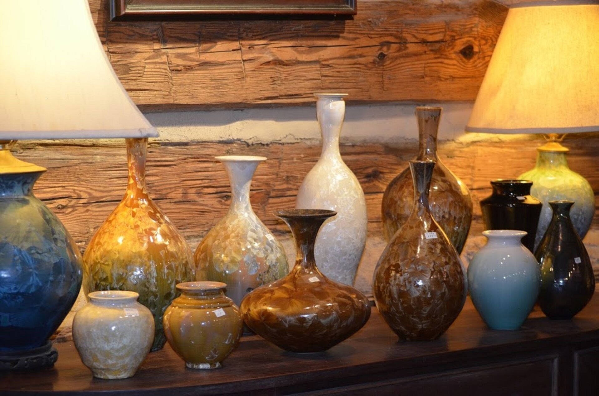 A collection of variously shaped and colored glass vases displayed on a wooden surface.