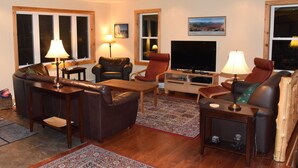 A living room with a sofa, two armchairs, a coffee table, a TV, and a fireplace.