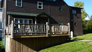A two-story building with a wooden deck and a green roof.