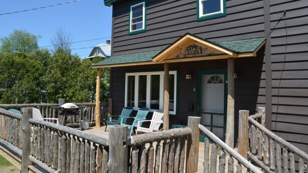 A two-story building with a porch, outdoor seating, and a wooden fence.