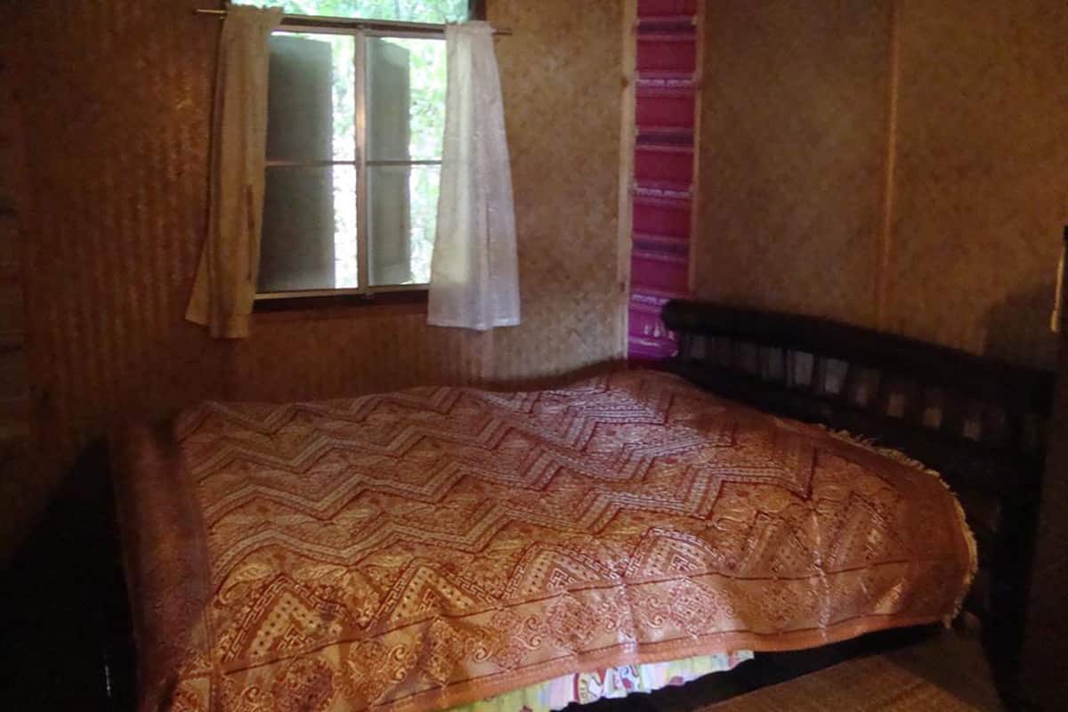 A room with a bed, a window with curtains, and a pink wall.