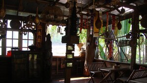 A rustic interior with wooden furniture, a bar area, and a view through a window. - Baan Suan Jantra Home Stay (Chiang Rai)