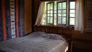A room with a bed, a window with curtains, and a wall with patterned fabric. - Baan Suan Jantra Home Stay (Chiang Rai)