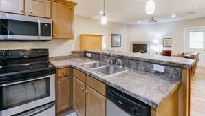 A kitchen with granite countertops, stainless steel appliances, wooden cabinets, and pendant lighting.