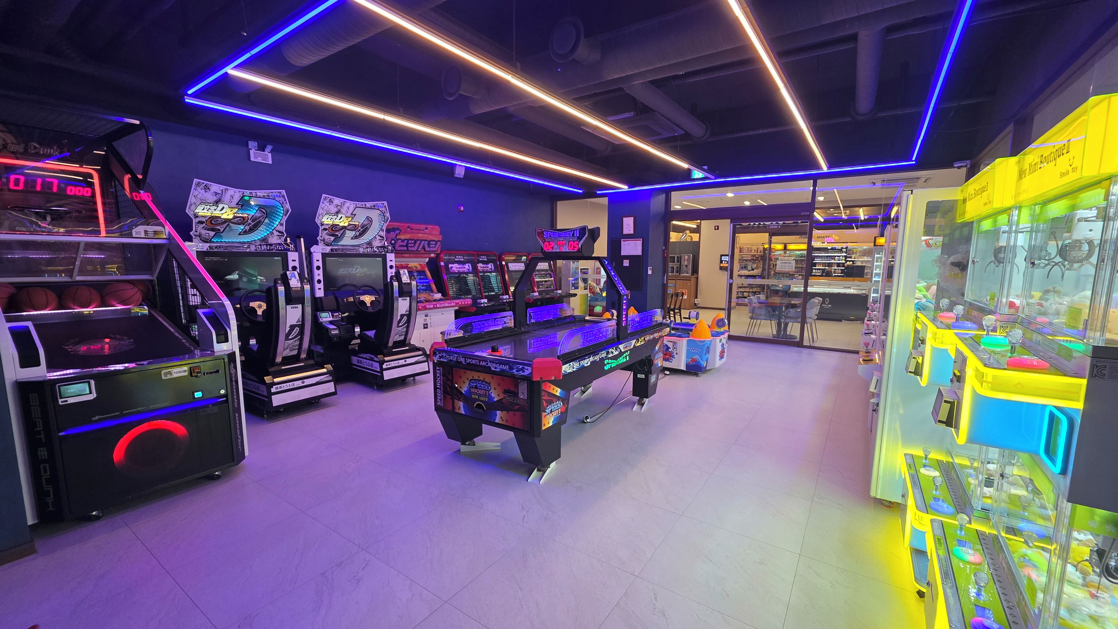 An indoor arcade with various gaming machines, including racing and sports games.