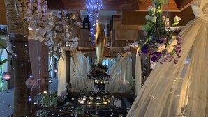 Una habitación con techo de madera rústica, un candelabro y un altar decorado con flores y velas.