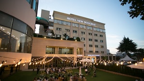 Un hotel con fachada moderna, zona de estar al aire libre y luces colgantes.