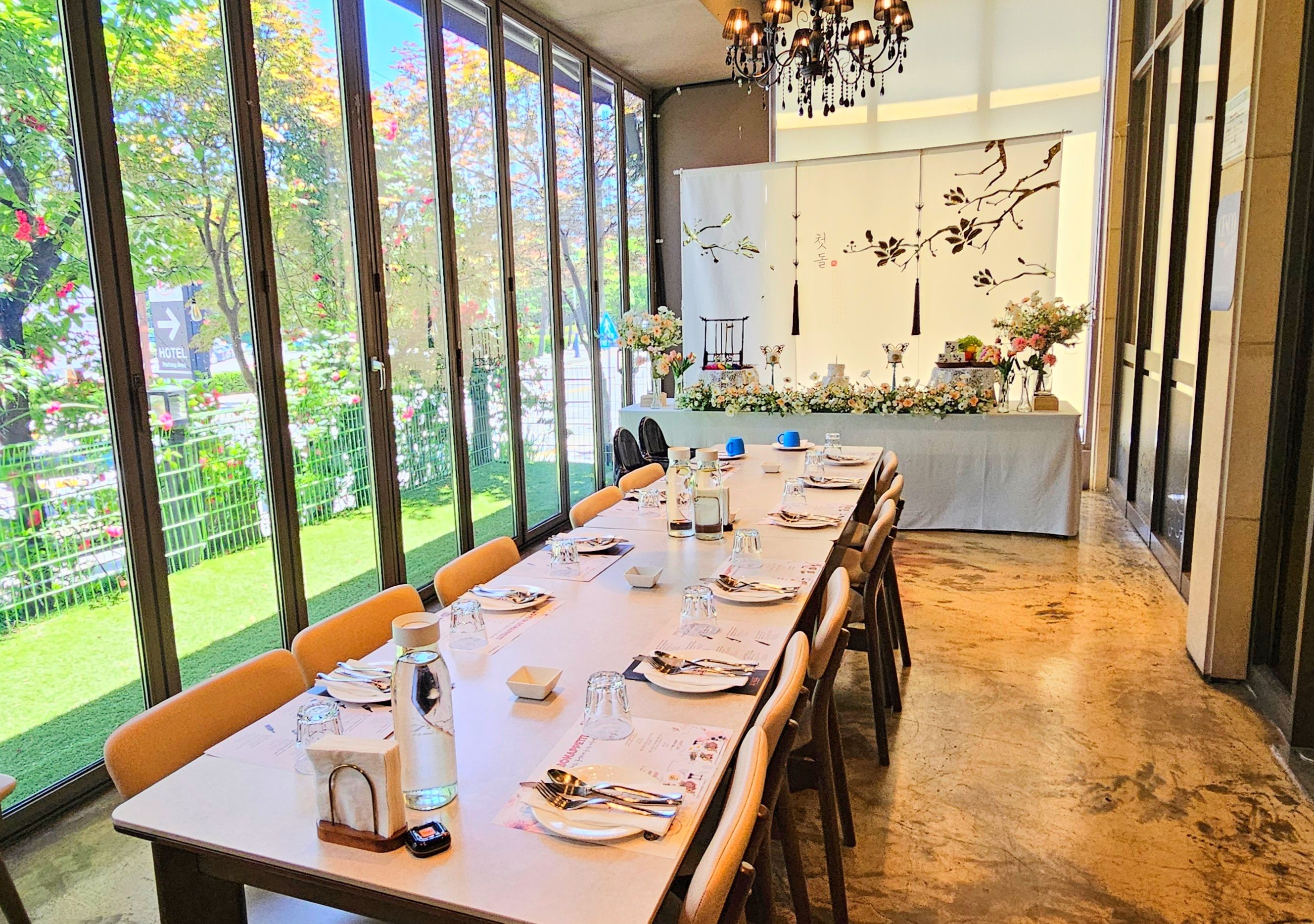 Un comedor con una larga mesa dispuesta para una comida, ventanas amplias y vistas al exterior.