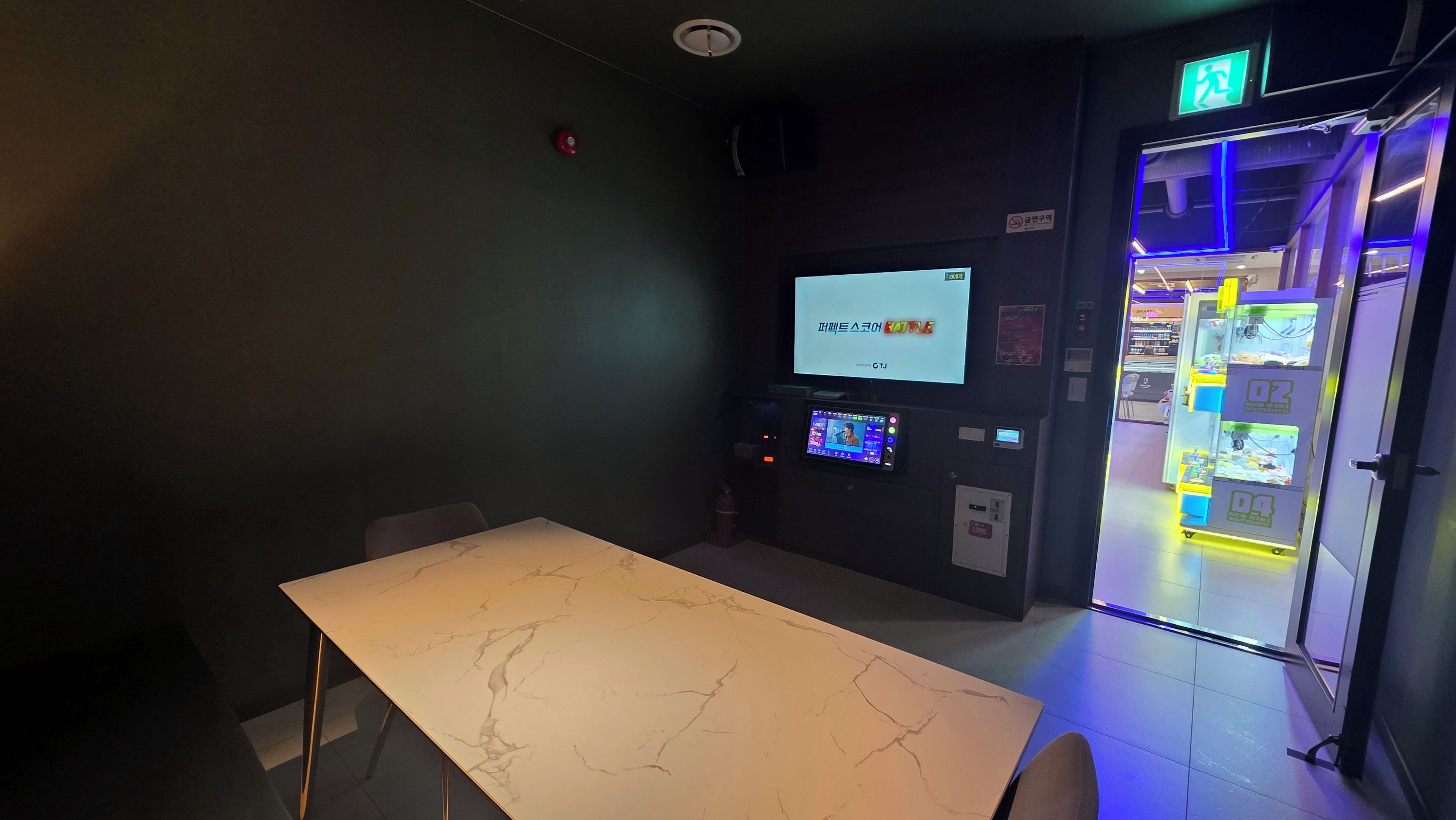A room with a marble table, a television screen, and a vending machine.