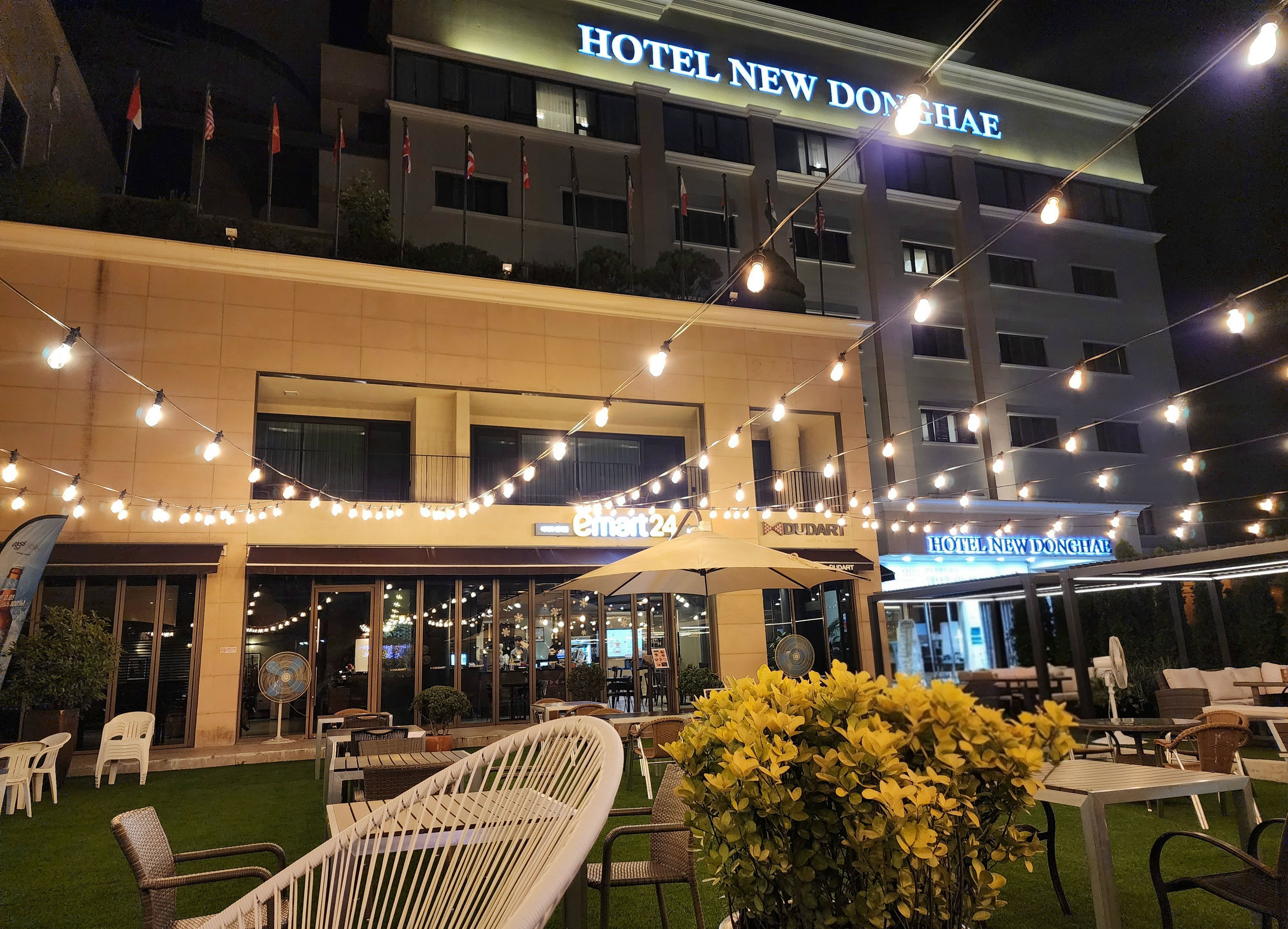 A hotel exterior with outdoor seating and string lights.