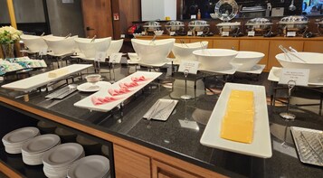 Disposición de bufé con diversos alimentos y utensilios de servicio.