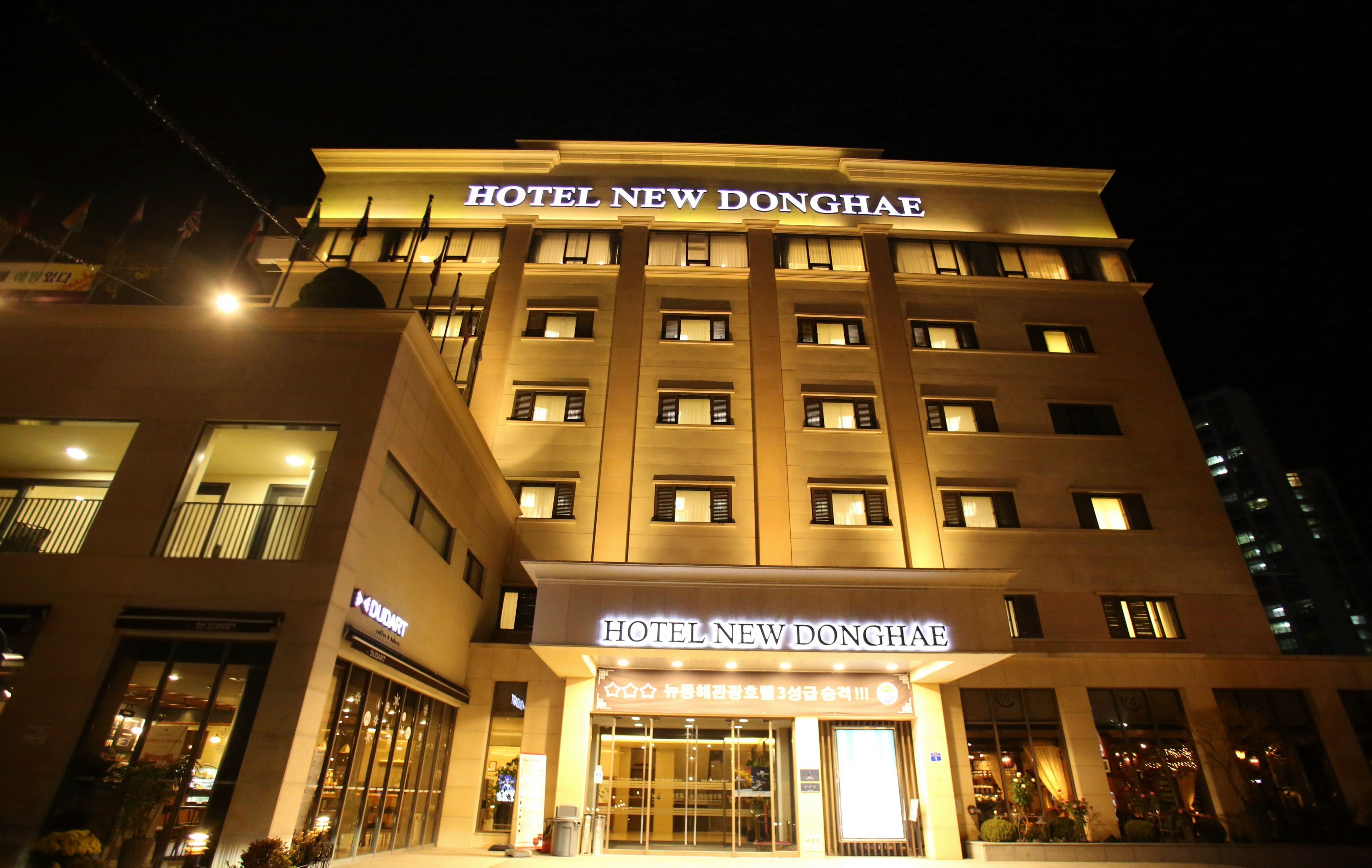A multi-story hotel with illuminated signage reading 'HOTEL NEW DONGHAE'.