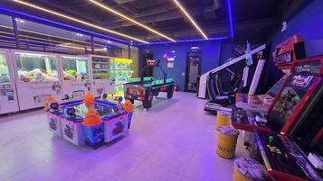 A gaming arcade with claw machines and racing simulators.