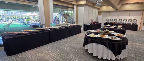 A buffet setup with multiple tables covered in black cloths, featuring an array of dishes.