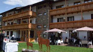 A hotel with outdoor seating, a deer sculpture, and a stone facade. - Olympic Regina Hotel (Giustino)