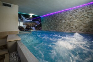 A spa area with a hot tub, stone walls, and a waterfall feature. - Olympic Regina Hotel (Giustino)