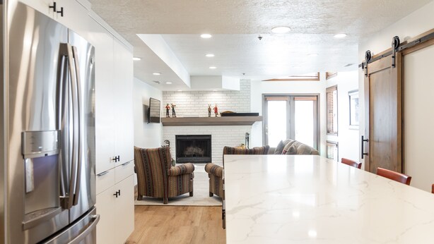 A modern kitchen with a large island, stainless steel appliances, and a fireplace.
