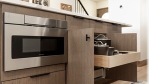 A modern kitchen with a built-in stainless steel oven, wooden cabinetry, and a wooden countertop.
