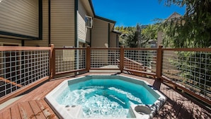 A hot tub on a wooden deck with a wooden fence.