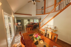 A spacious dining area with a wooden table, chairs, and a view of the kitchen and living room. - Beautiful updated River cottage in rural Upshur County. Backroads and backwoods for miles with fiber internet, four bedrooms and 3.5 baths. Dark skies, stocked river, adventures await. (Tallmansville)