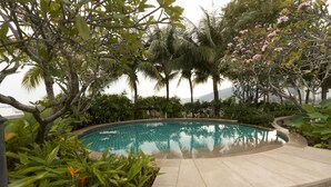 En swimmingpool omgivet af frodig vegetation og palmer.