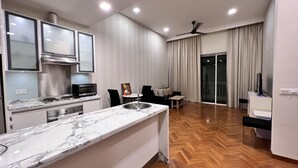 Et moderne køkken med marmor bordplade, indbyggede hårde hvidevarer og et spiseområde med sofa og bord.