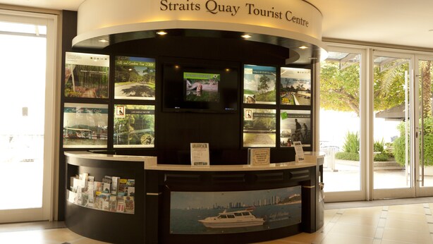Turistcenter med en buet receptionsdisk, informationsskærme og et stort vindue der giver udsigt til det fri.