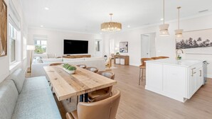 A modern living room with a wooden dining table, sofas, and a TV.