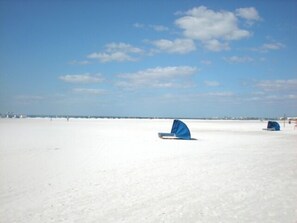 A wide, open sandy area with a clear sky and a few clouds.