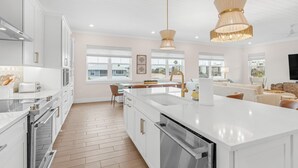 A modern kitchen with white cabinetry, a large island, and pendant lighting.