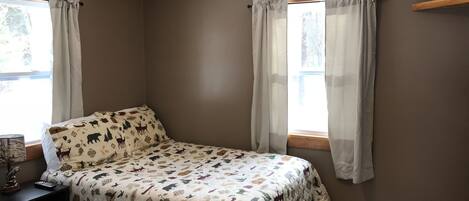 Une chambre avec deux lits, une télévision et une fenêtre avec des rideaux.