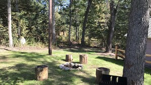 Un espacio al aire libre con césped, troncos de madera y una parrilla.