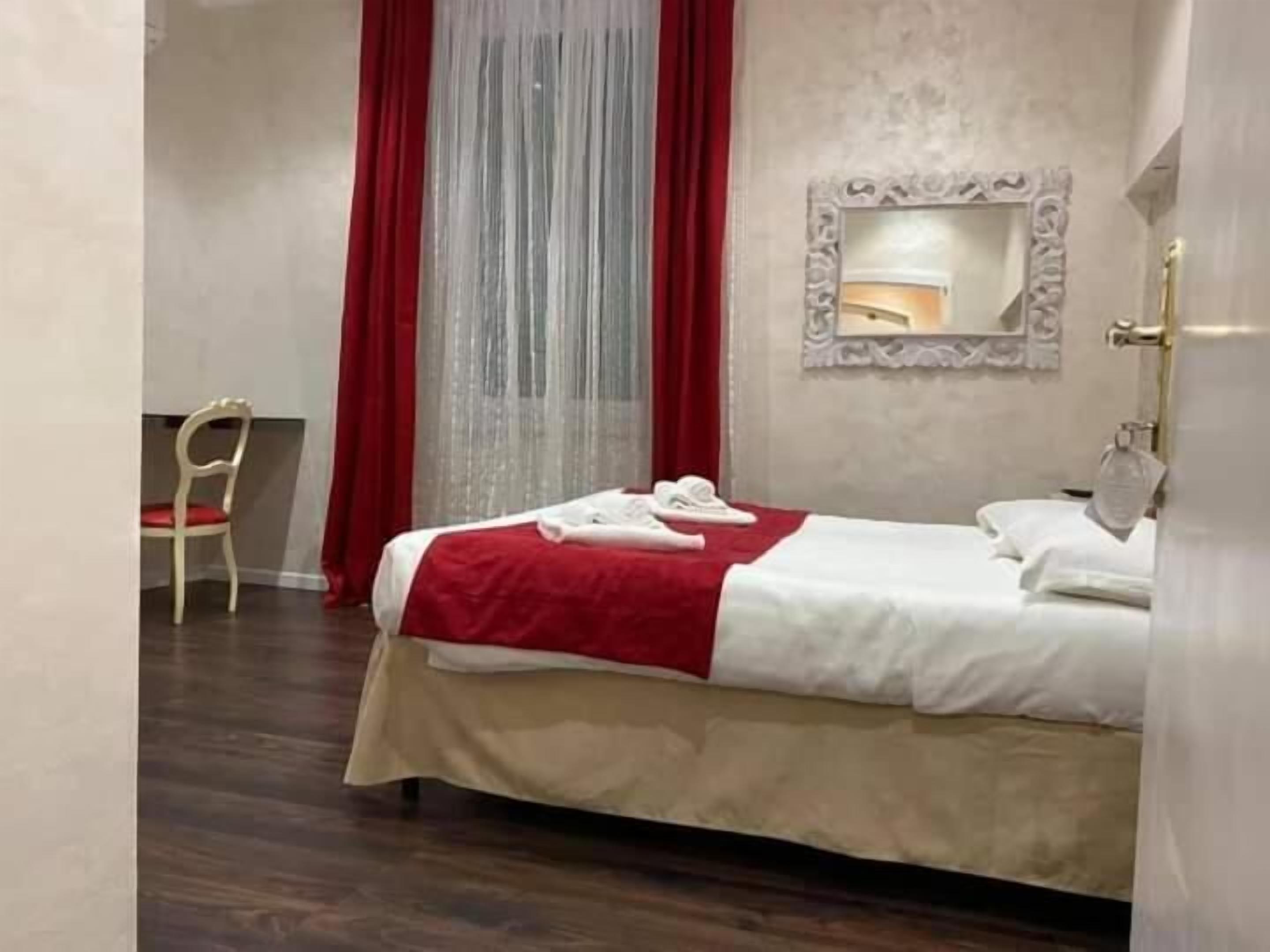 A hotel room with a bed, a chair, and a mirror.