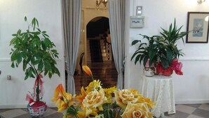 A room with a checkered floor, a potted plant with yellow flowers, and a table with a white tablecloth. - Antico Hotel Moderno (Piombino)