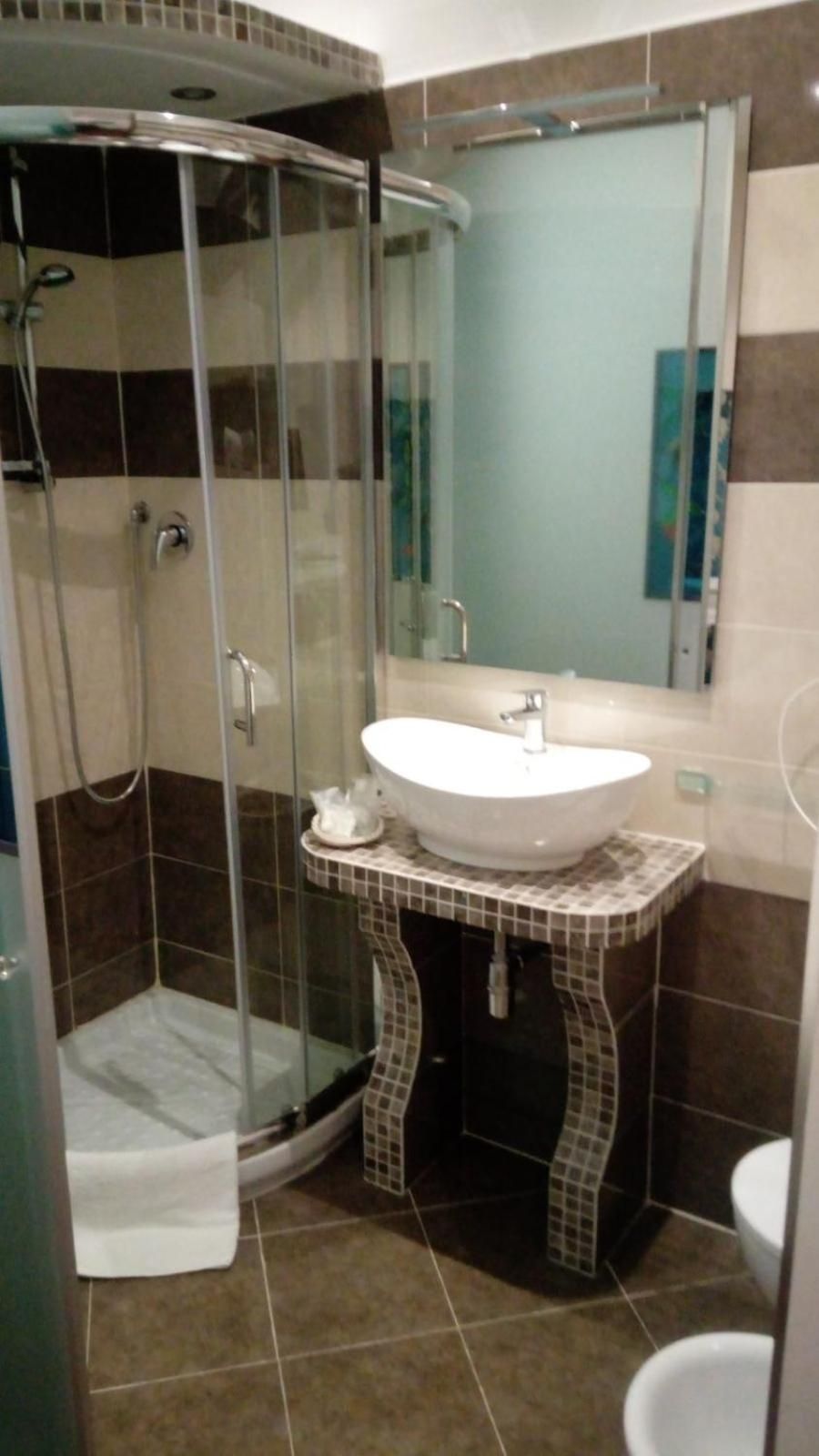 A bathroom with a glass-enclosed shower, a white sink, and a tiled vanity.