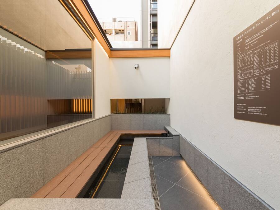 A modern interior with a narrow corridor, a small water feature, and a wall-mounted information board.