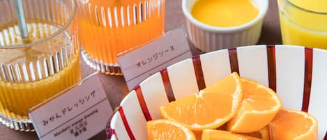Una mesa con un bol de naranjas en rodajas, un vaso de jugo de naranja y un recipiente pequeño con yema de huevo.