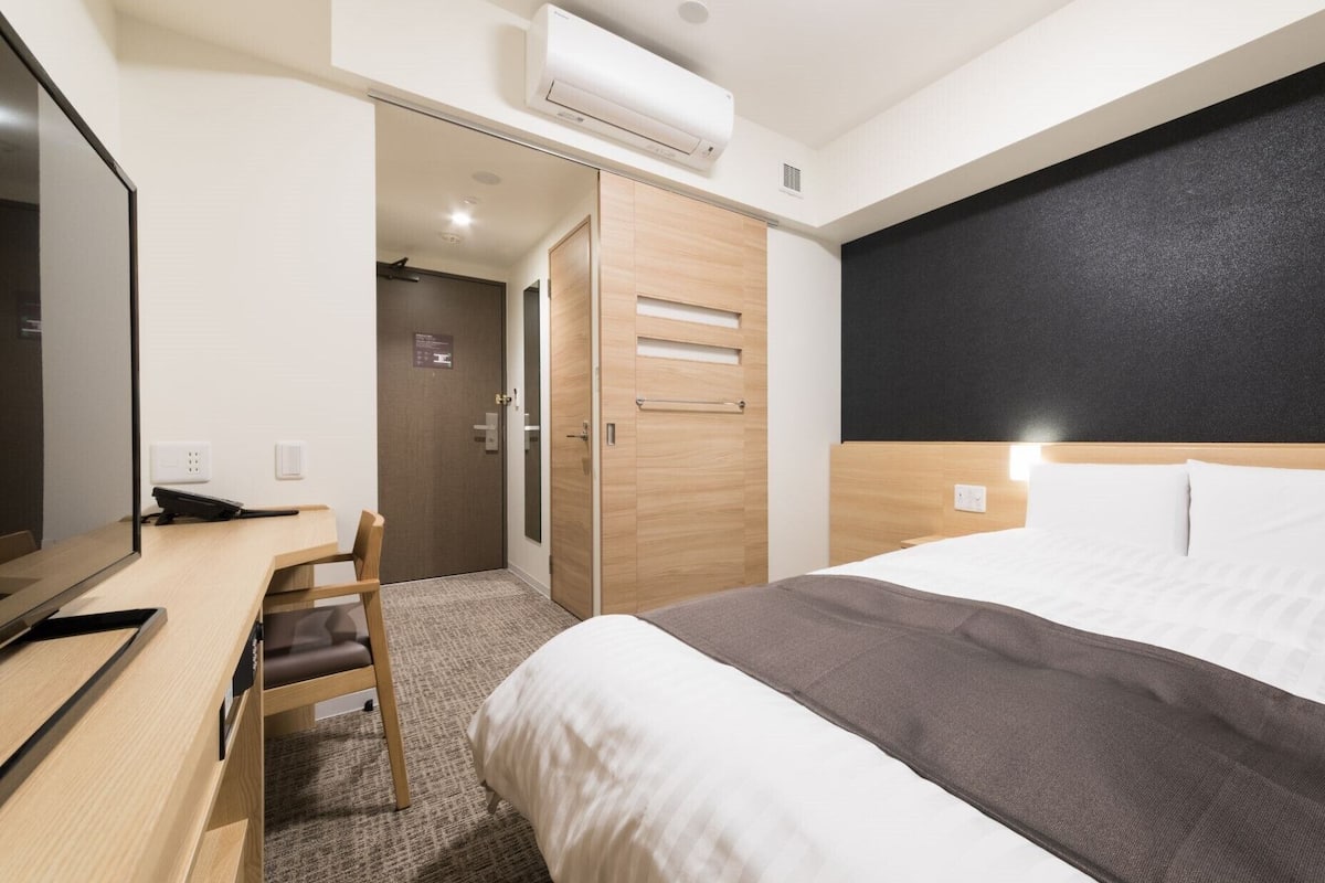 Une chambre d’hôtel équipée d’un lit, d’un bureau, d’une chaise, d’une armoire et d’un appareil de climatisation.