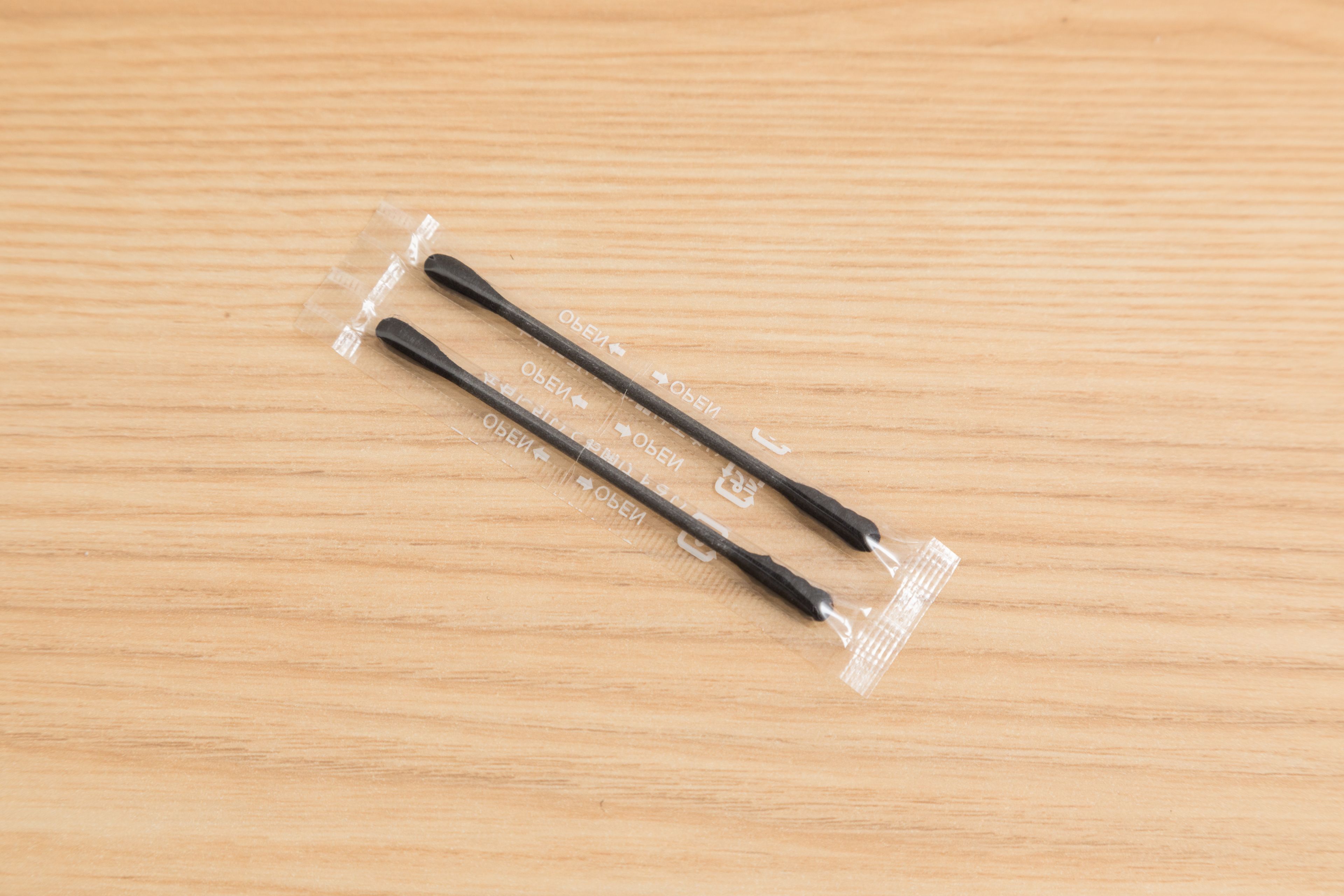Zwei schwarze Stifte mit transparenter Verpackung auf einer Holztischplatte.