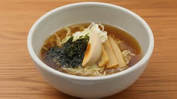 Een kom ramen met zeewier en tofu op een houten tafel.