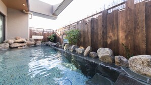 Une piscine à l’eau claire, entourée de rochers et d’une clôture en bois.