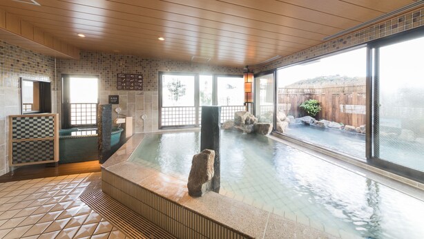 Un espace spa doté d'un jacuzzi, de murs carrelés et de grandes fenêtres.