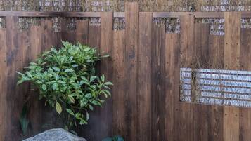 A wooden fence with a plaque, a small rock garden, and a water feature.
