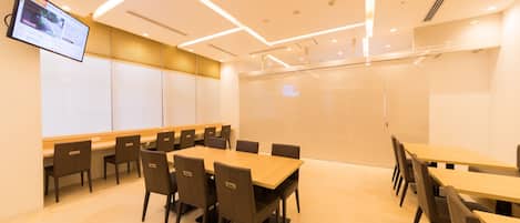 Una sala de conferencias con una gran mesa y sillas, un televisor de pantalla plana en la pared y un diseño moderno en el techo.