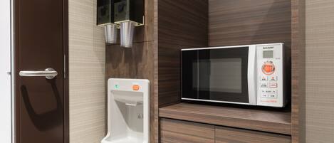 A microwave oven on a wooden cabinet, a hand dryer, and a door with a handle.