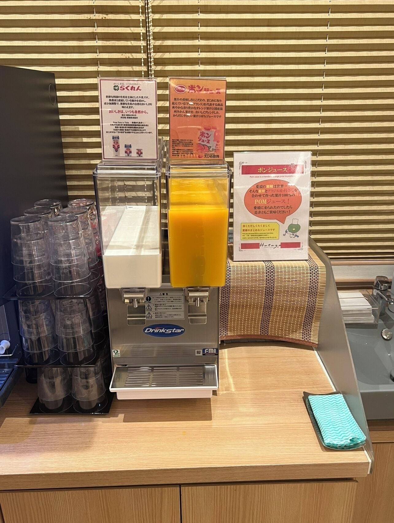 A beverage station with a drink dispenser, clear plastic cups, and informational signs.