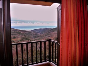 A balcony with a view of a mountainous landscape and a body of water.