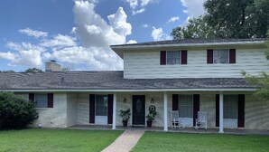 A two-story house with a front porch, a pathway leading to the entrance, and a lawn. - Big family friendly house Close to Texas A&M (Bryan)