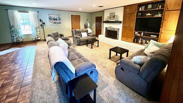 A living room with a fireplace, a sofa set, a television, and a bookshelf. - Big family friendly house Close to Texas A&M (Bryan)