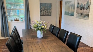 A dining room with a wooden table, black chairs, a vase with flowers, and artwork on the walls. - Big family friendly house Close to Texas A&M (Bryan)